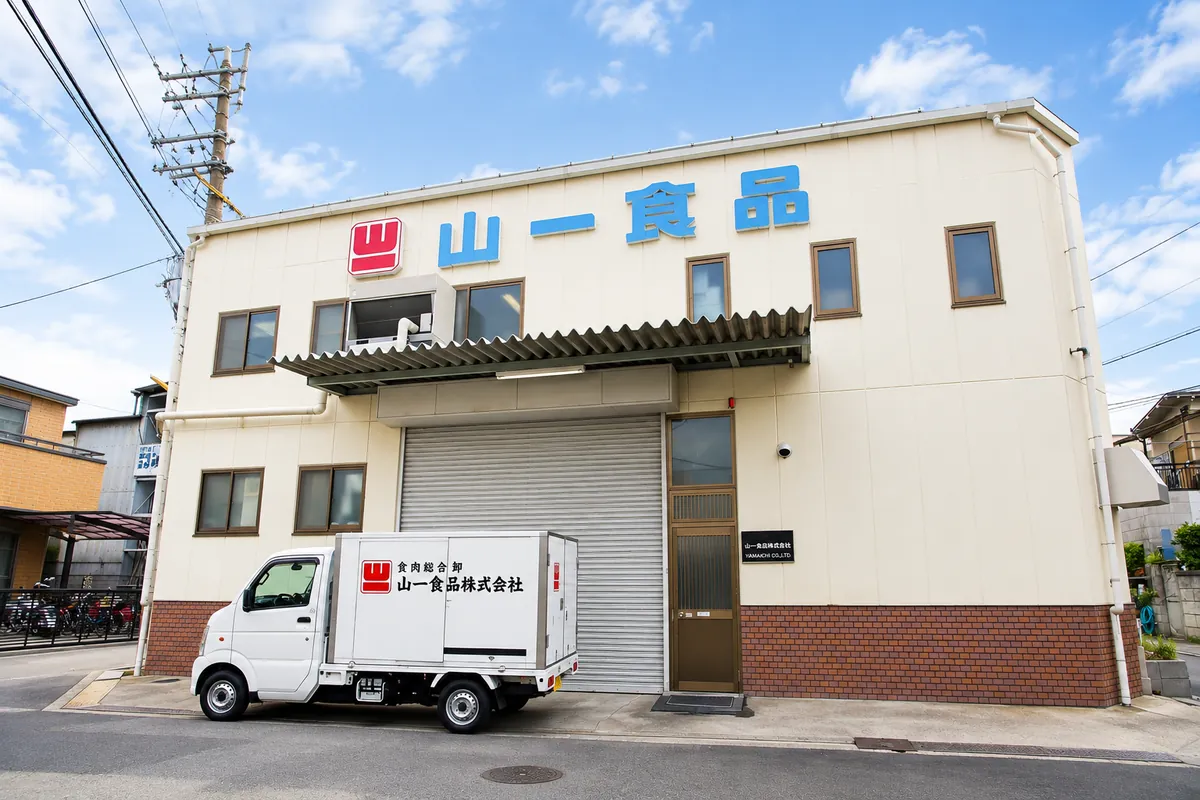 「山一食品」の看板を掲げた社屋と配送車